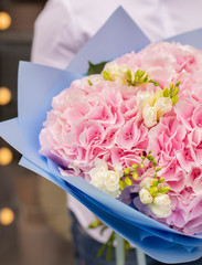Young man holding a big bouquet of pink hydrangea and freesia in Women's day. Fresh bouquet flowers.