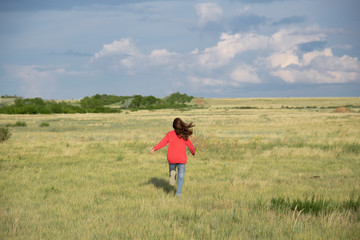A girl runs across the field in the summer.