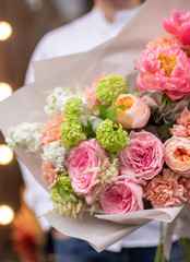 Flower shop. Beautiful bouquet of mixed flowers in man hands. The work of the florist at a flower shop. Delicate bright color. Fresh cut flower.