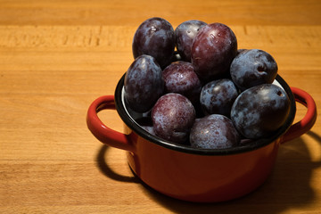 fresh blue plum in a red metallic pot table top