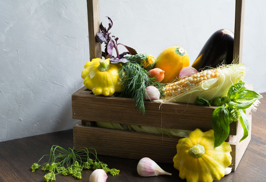 vegetables: corn, zucchini, eggplant, carrots, garlic, herbs are  in a wooden basket
