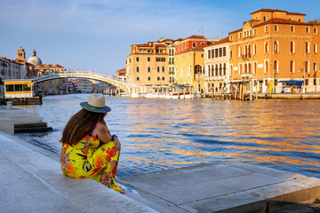 Tourist sitting on the edge of the Grand Canal in Venice, admiring the city landscape of Venice, Italy