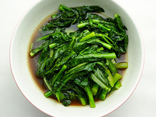 stir fried kale with oyster sauce in white bowl on white background
