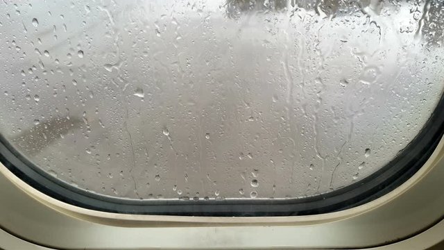 Raindrops on airplane window. Bad weather during takeoff. Airplane window with raindrops falling