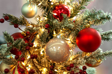 Obraz na płótnie Canvas Decorated Christmas tree closeup background. Red and silver balls and illuminated garland with flashlights. New Year baubles macro photo with bokeh. Winter holiday decoration