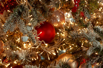 Decorated Christmas tree closeup background. Red and silver balls and illuminated garland with flashlights. New Year baubles macro photo with bokeh. Winter holiday decoration