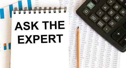 The inscription on the paper tablet: ask the experts. next to accounting and a mug of coffee.