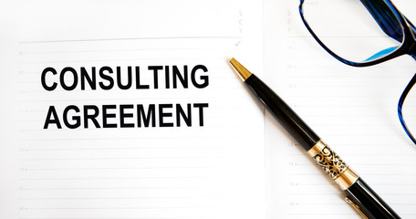 Inscription on a sheet of paper from the daily CONSULTING AGREEMENT, next to glasses, pencil.