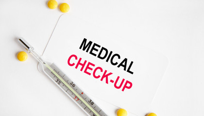 Overhead view of clipboard and white sheet written with MEDICAL CHECK-UP inscription on wooden background. Medical and healthcare concept.