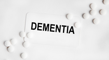 The inscription on the BUSINESS card DEMENTIA, next to lie yellow tablets and a thermometer.