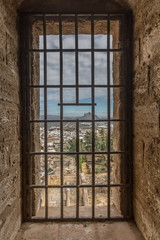 Fototapeta na wymiar View of the city and the Peña de los Enamorados or the Lovers' Rock through a window with wrought iron grille in the Alcazaba de Antequera, wonderful day in the province of Malaga Spain