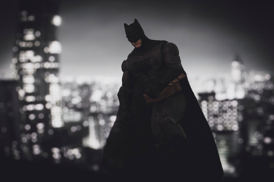 NEW YORK USA, AUGUST 21 2020: Batman from DC Comics looming over Gotham City at night - Mattel action figure