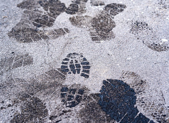 Human foot print. trail of male shoe footprints, black oil on grey pavement. close-up with copy space