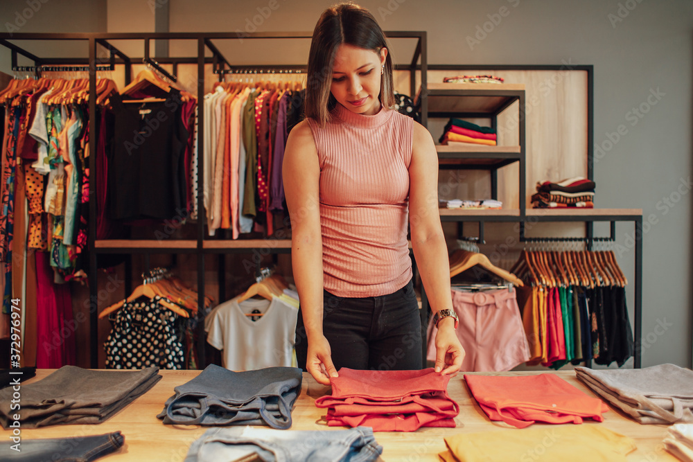 Wall mural Latin woman owner of small business. Entrepreneurial woman working in her clothing store.