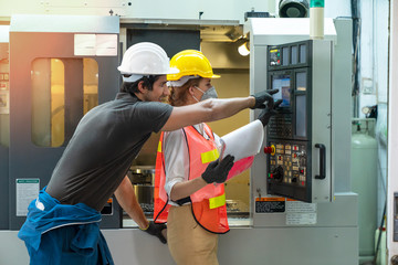 Female industrial engineers have to consult with colleague while using clipboard. Supervisor,worker with hard hat working in manufacturing factory on business day. Concept of workplace gender equality