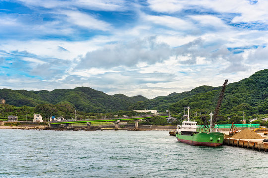Coast of the Bōsō Peninsula with the loop ramp of the Futtsu Kanaya Interchange along the Uraga Channel and a sand carrier ship mooring in front of the Mount Nokogiri.