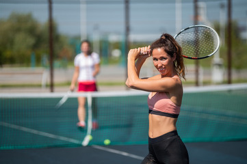 Sportive caucasian woman posing with a racket on a tennis court outdoors.