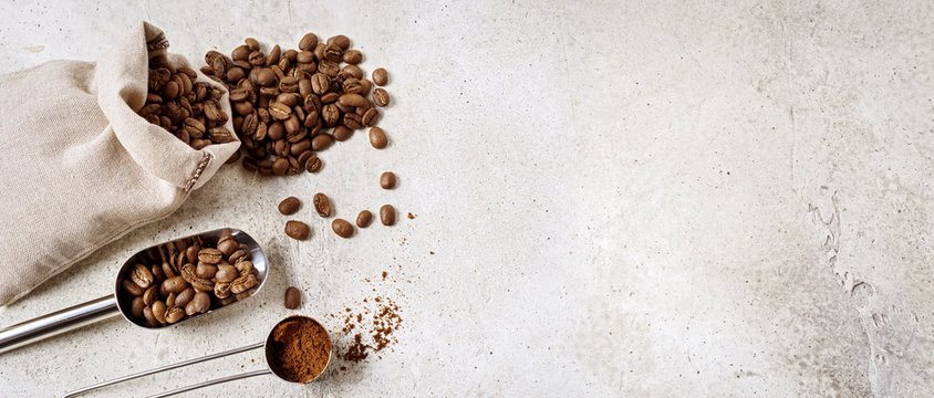 Coffee beans bag with scoop and spoon on concrete biege background with copy space