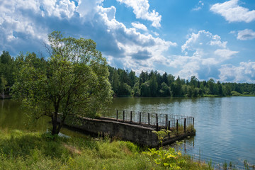 A spillway to a reservoir with a beautiful cloudy sky on a summer day.