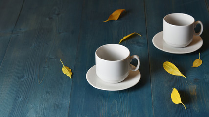 Two empty coffee cups on a blue wooden desk under morning sun