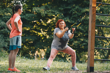 Obraz premium An obese woman in nature doing weight loss training, the trainer watches from the side