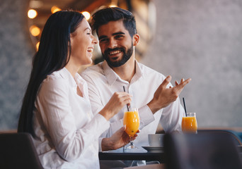 The couple sitting in a restaurant, drinking orange juice and talking about business