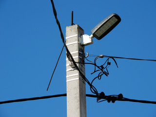 Street lamp on a pole close-up against the blue sky.