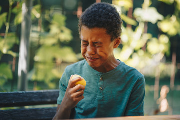 African child eating lemon and frowning