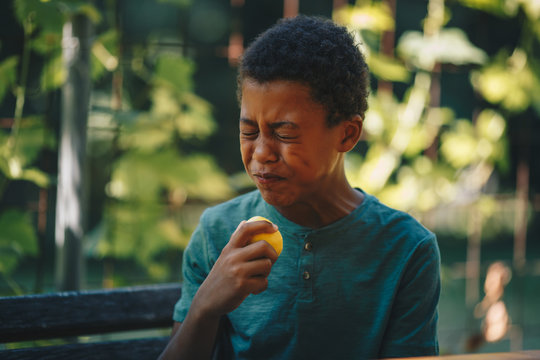 African Child Eating Lemon And Frowning