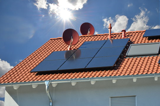 Solarthermische Anlage, Photovoltaik-Anlage und Sateliten-Antenne auf einem Ziegeldach montiert