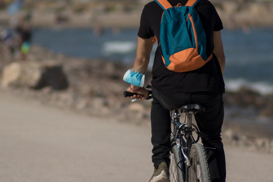 Hombre en una bicicleta con la mascarilla en el antebrazo
