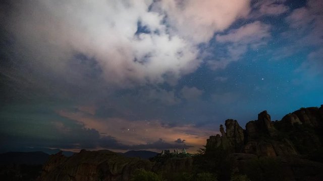 Amazing night time lapse with Milky Way galaxy, moving clouds, plane trails and meteor shower, during Perseid Stream over picturesque rock formation, Belogradchik rocks, Bulgaria