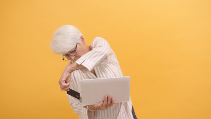 Puzzled senior woman trying to insert credit card in the laptop. Online shopping . High quality...