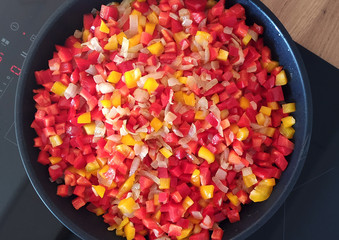 Summer dinner in the pan. Red and yellow peppers and onions.