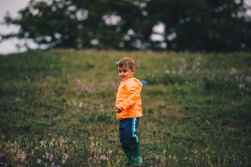 The boy stands alone in the meadow and holding a toy airplane in his hand