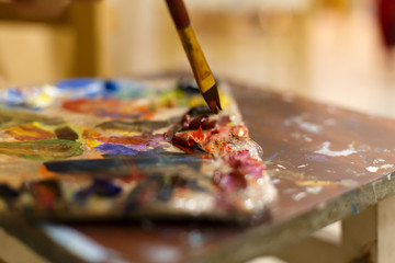 Close-up of an easel with paints, the artist paints a brush. Painting a picture.