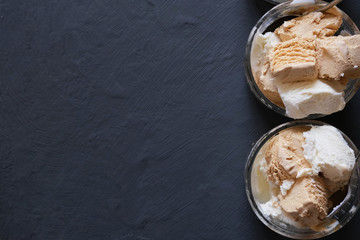 Ice cream in a glass bowl on a dark table.
Place for your text.
