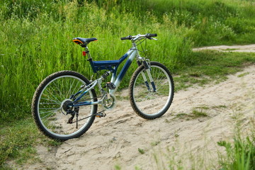 Fototapeta premium beautiful mountain bicycle is on sand road on green nature background at sunset