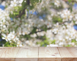 empty wooden table on a spring blurred background with flowering branches.