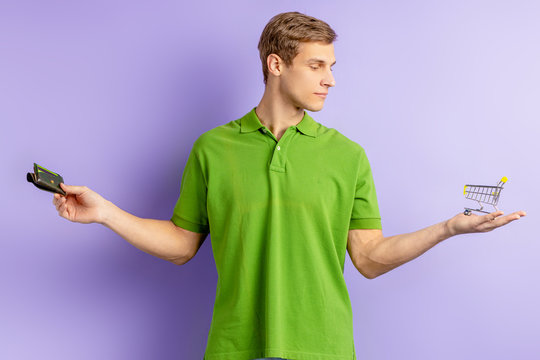 Young Caucasian Man Holding Toy Truck In One Hand And Wallet In Other, Going To Shop, Choose Between Shopping And Economy