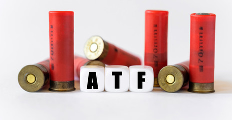 Fototapeta Against the background of rifle cartridges, there are white cubes with text ATF. obraz
