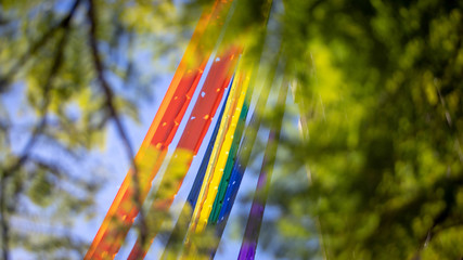 Rainbow gay pride flag against blue sky over building, space for text. LGBT concept