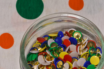 colored thumbtacks in a glass jar
