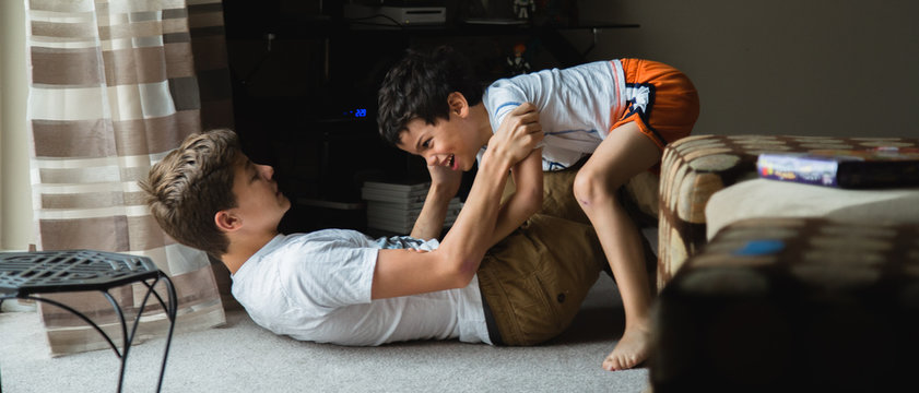 little boy is having fun playing with his brother wrestling on the floor 