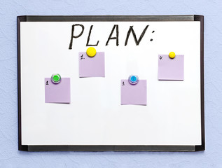 white board with a plan and colored sheets of paper for notes, on a light wall
