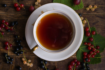 Vintage cup of tea with gold decoration on the old wooden table on which berries lie
