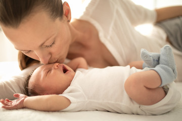 Obraz na płótnie Canvas Mother kissing her adorable newborn baby girl 