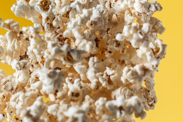 Cheesy popcorn flying in front of the yellow background