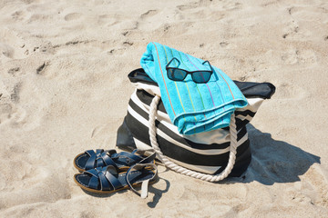 Set of personal belongings lying on the beach sand with in bright summer day