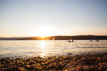 Children have fun on river at summer sunset